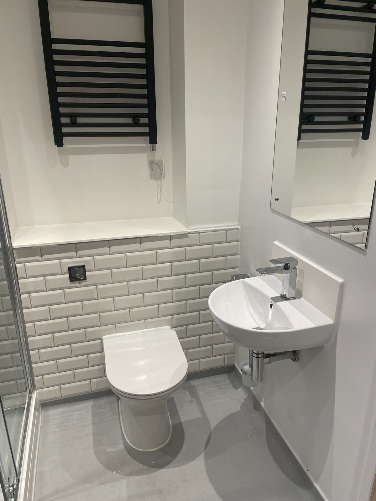 Finished bathroom with toilet, basin, metro tiles and towel rail